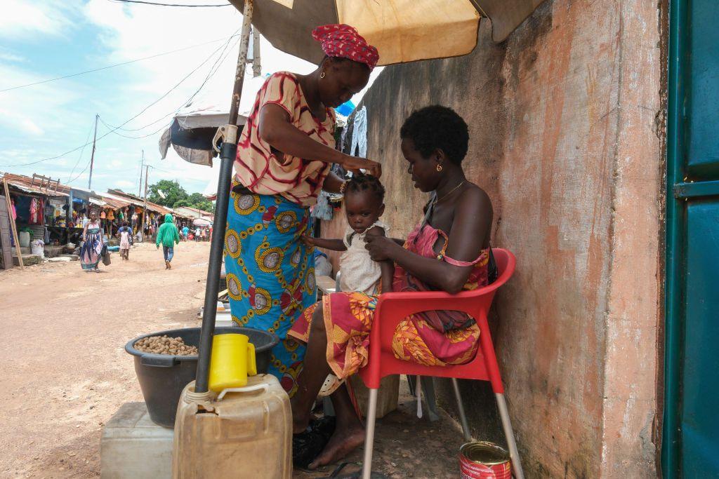 Women tend to a child as they sell peanuts at an outdoor market in Bissau- Monday 30 September 2024