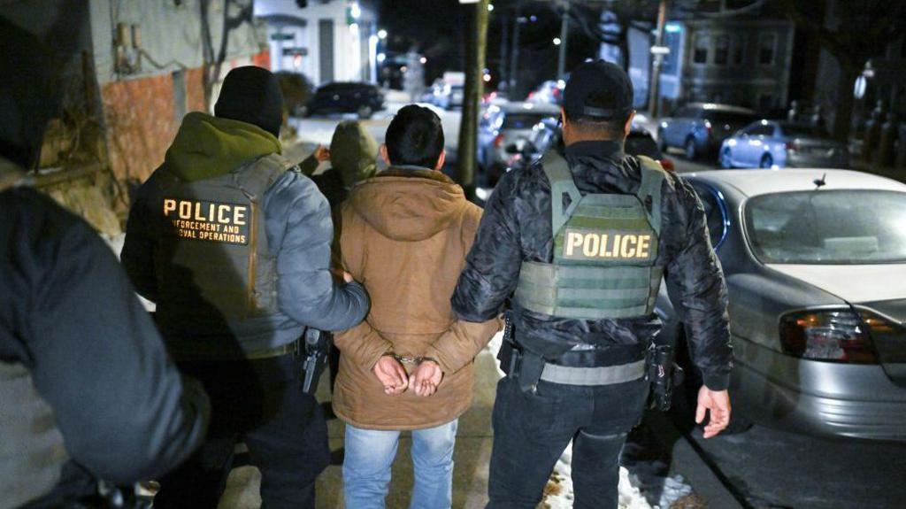 Undocumented migrant being taken into custody of officers in New York City on 28 January. 