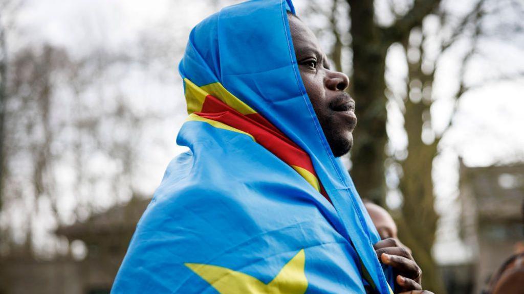 An image of a man wrapped in the DR Congo flag while he attends a protest in Belgium - Saturday 8 February 2025