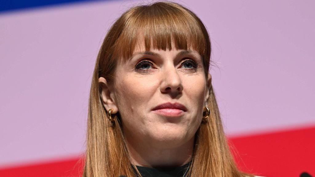 Angela Rayner against a red-and-pink background