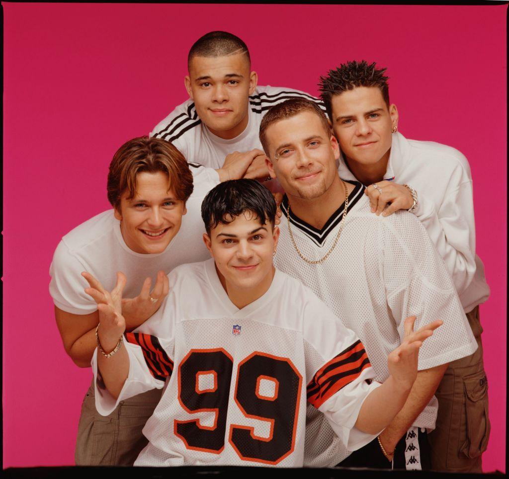 An archive picture of the boyband Five sees them posing in baggy white t-shirts against a bright pink background