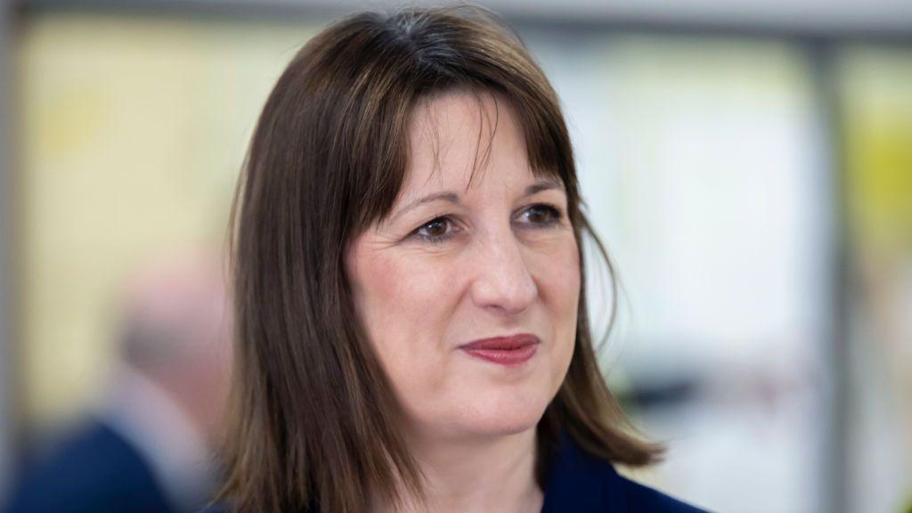Rachel Reeves dressed in a navy blue suit jacket gives a half-smile