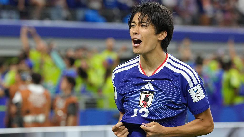 Keito Nakamura celebrating a goal by pulling his Japan shirt