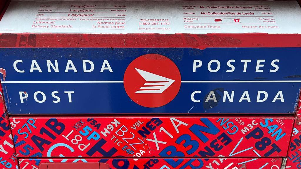 A red Canada Post mail box, emblazoned with its logo