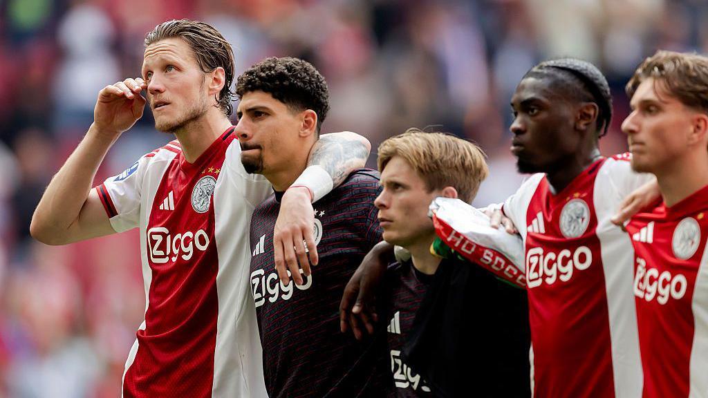 Ajax players stand with their arms around each others' shoulders