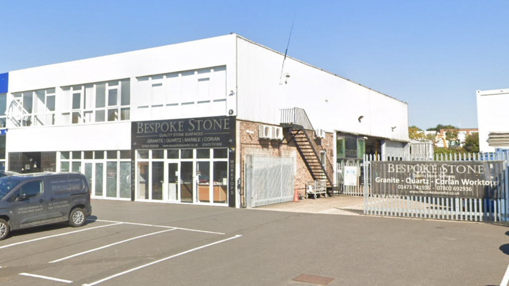 Bespoke Stone's workshop on Dales Road, Ipswich. It is a white building with a warehouse at the back. A car park is at the front of the building