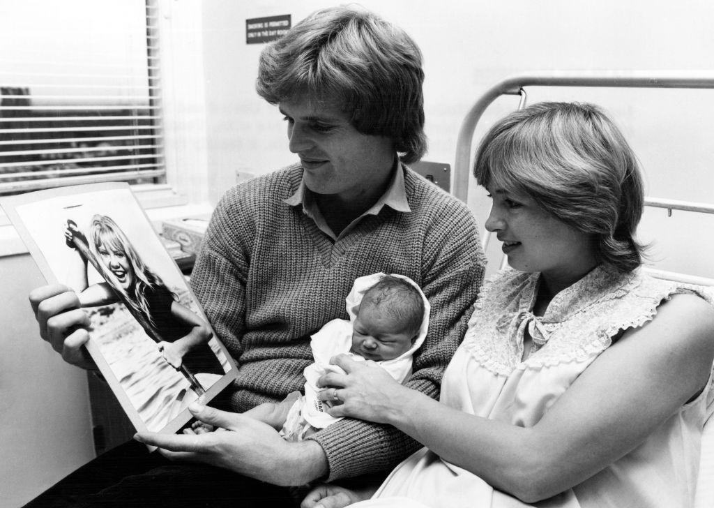 Footballer Gordon McQueen and his wife Yvonne hold newborn daughter Hayley while looking at a photograph of film star Hayley Mills, who their child is named after