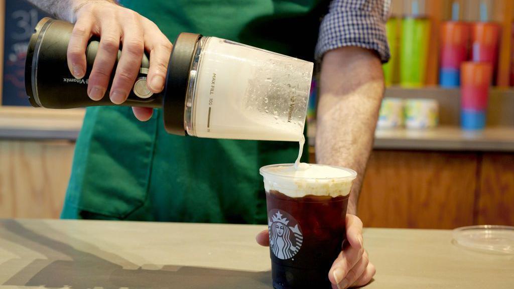 A barista pours a cold foam at a Starbucks branch in New York, US