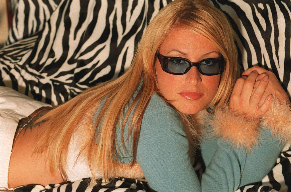 Anastacia reclining on a zebra-striped sofa