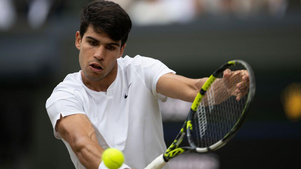 Carlos Alcaraz hits returns a backhand at Wimbledon.