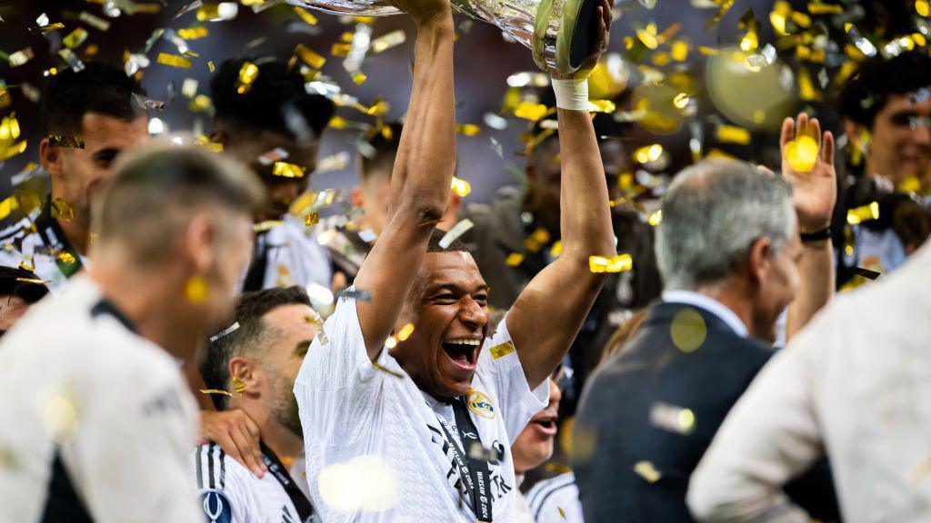 Mbappe lifts the Uefa Super Cup, smiling, surrounded by teammates and confetti