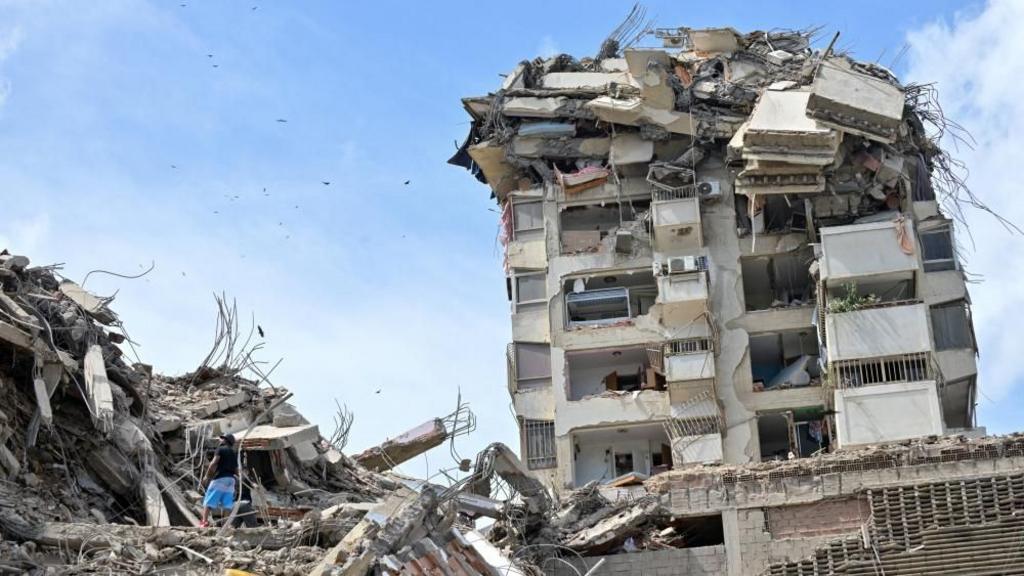 People search for casualties amid the rubble of collapsed buildings, in the aftermath of earthquakes in La Guaira, Venezuela
