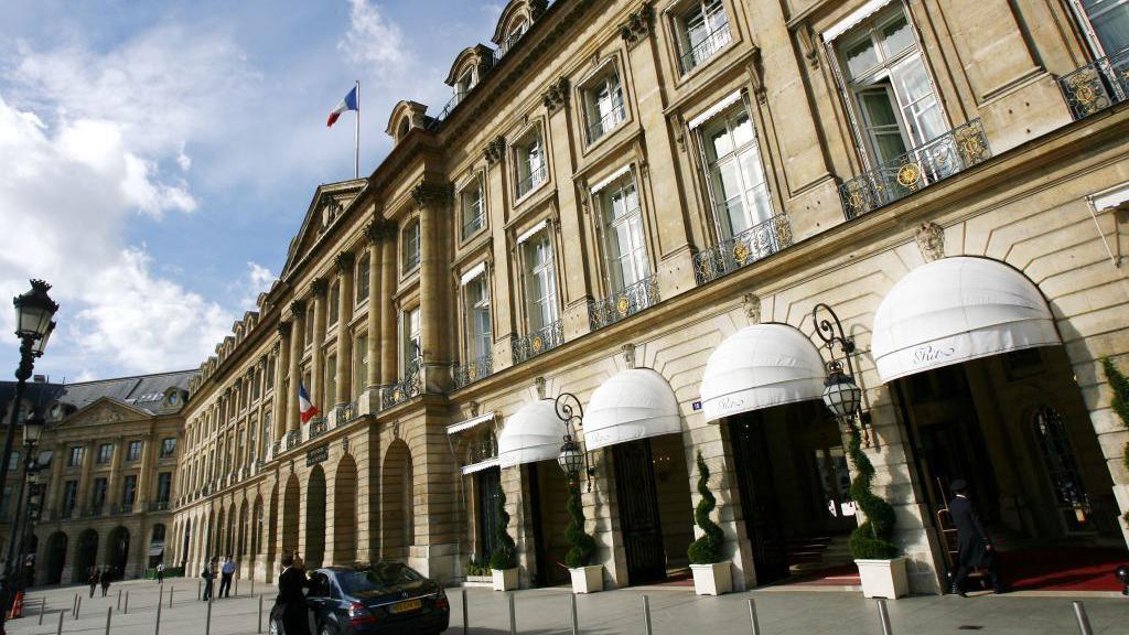 The facade of the Hotel Ritz Paris, a grand stone building with white, domed awnings above it's four entrances