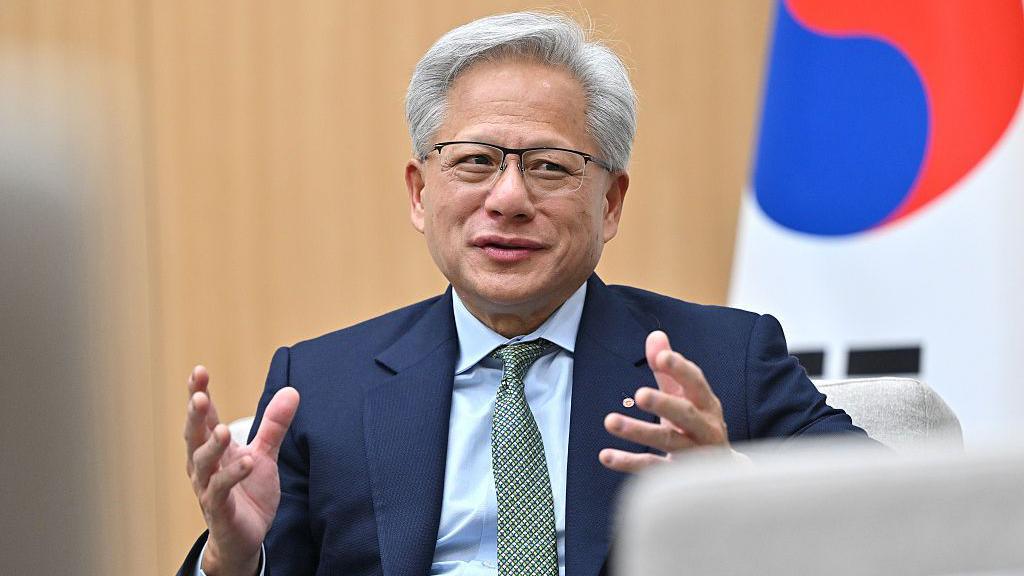 A man in a dark navy blue suit is sat in front of a South Korean flag