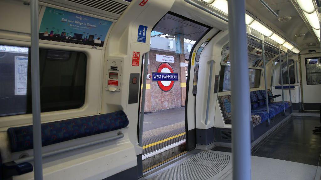 File image showing a general view of the signage of the West Hampstead Underground Station, taken from an empty Tube carriage with grey floors and poles and blue seats