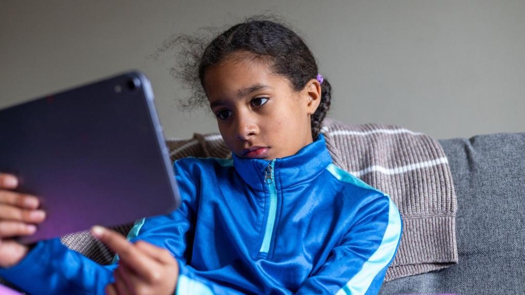 A girl looks at an iPad with a curious but bored expression.
