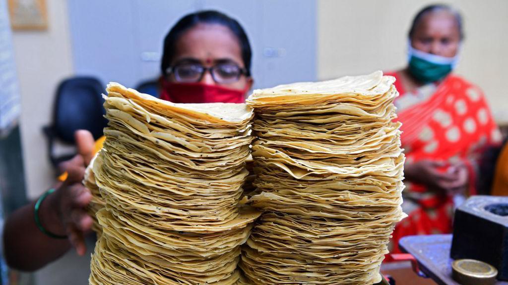 In this photograph taken on March 8, 2021, members of Shri Mahila Griha Udyog, the organisation that produces the famous Lijjat Papad, weighs papadums at one of the organisation's facilities in Mumbai. - The fairytale success of Lijjat Papad -- a multi-million-dollar venture founded by seven women in a crowded Mumbai tenement in 1959 with seed capital of 80 rupees (1.10 USD) -- belies its revolutionary feminist aspirations. - TO GO WITH India-economy-gender-food, FEATURE by Ammu KANNAMPILLY (Photo by Indranil MUKHERJEE / AFP) / TO GO WITH India-economy-gender-food, FEATURE by Ammu KANNAMPILLY (Photo by INDRANIL MUKHERJEE/AFP via Getty Images)
