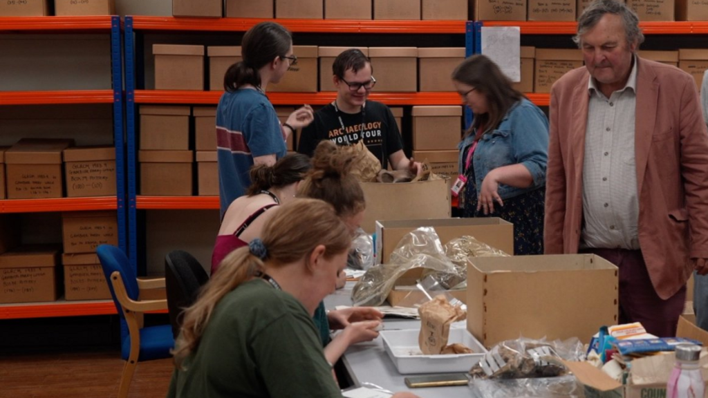 Mark Horton watching volunteers at a table who are unpacking boxes.
