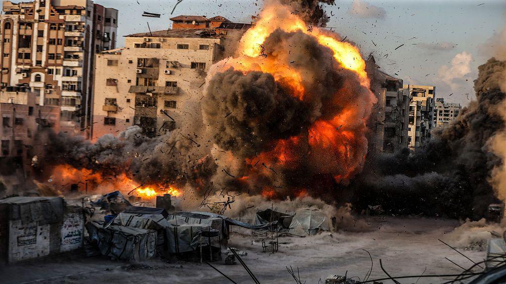 A huge ball of flame and black smoke fills the shot, as an air strike hits an urban centre in Gaza City.