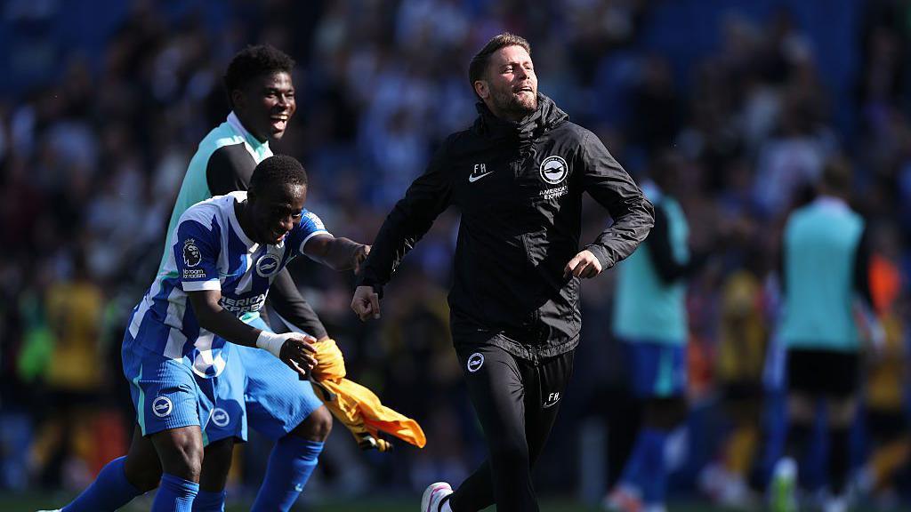 Yankuba Minteh and Carlos Baleba push Fabian Hurzeler towards the supporters to celebrate