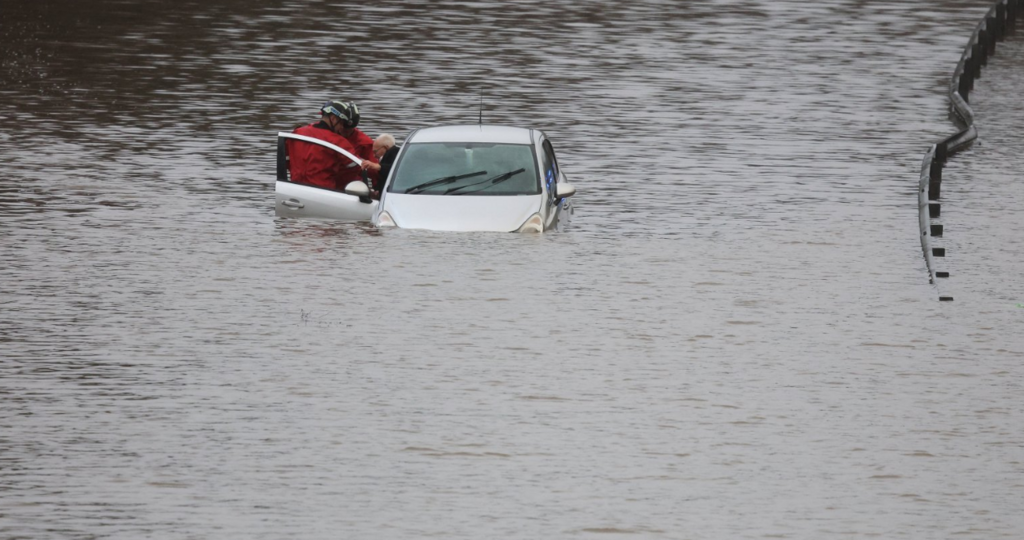 Firefighters rescue an elderly man from a flooded car in Stockport