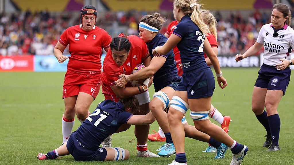 Sisilia Tuipulotu is tackled by several Scotland players