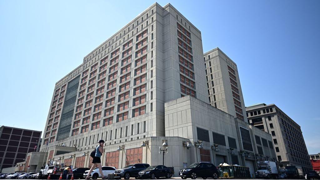 A woman using a mobile phone walks past the Metropolitan Detention Center in Brooklyn, New York. 