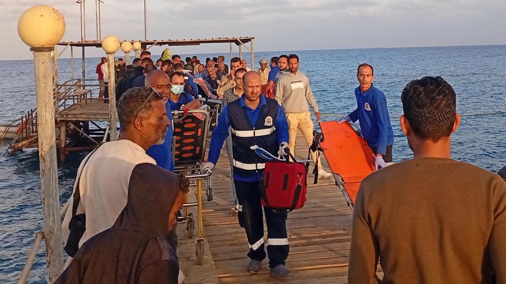 Medics and people wait for possible survivors after a boat sank at a harbour in Marsa Alam