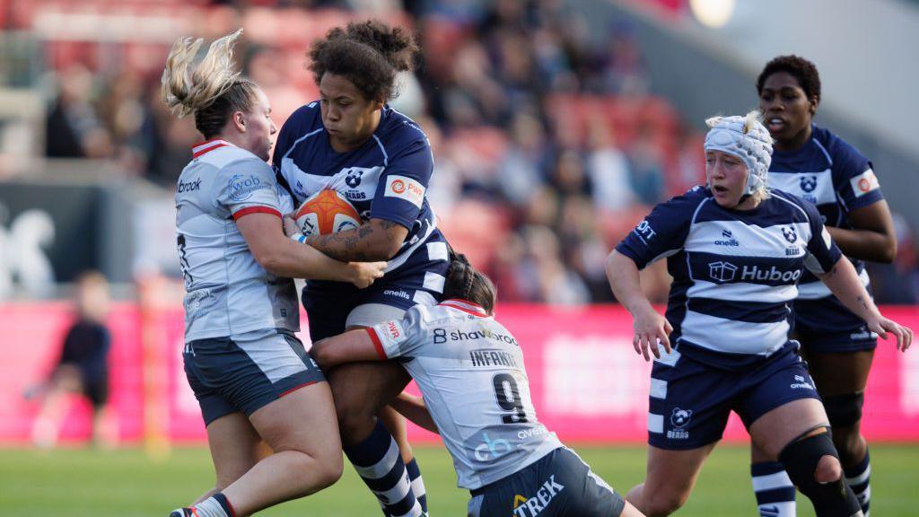 Rownita Marston-Mulhearn is tackled by two Saracens players 