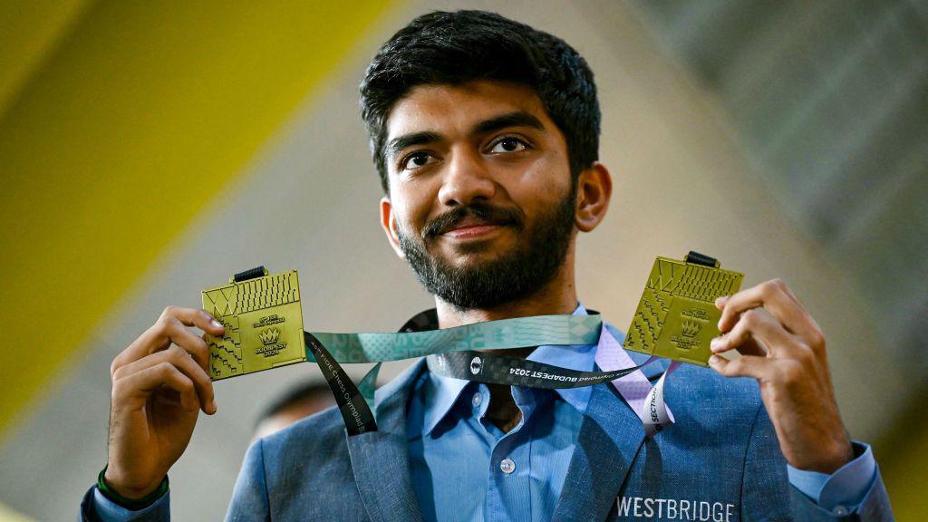 Gold medalist grandmaster Dommaraju Gukesh, shows his medals upon his arrival at the Chennai International Airport in Chennai on September 24, 2024, after his win at the 45th FIDE Chess Olympiad Budapest 2024. (