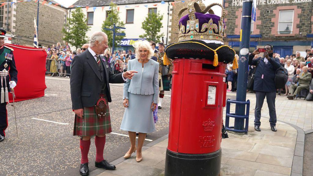 King and Queen looking at a post box