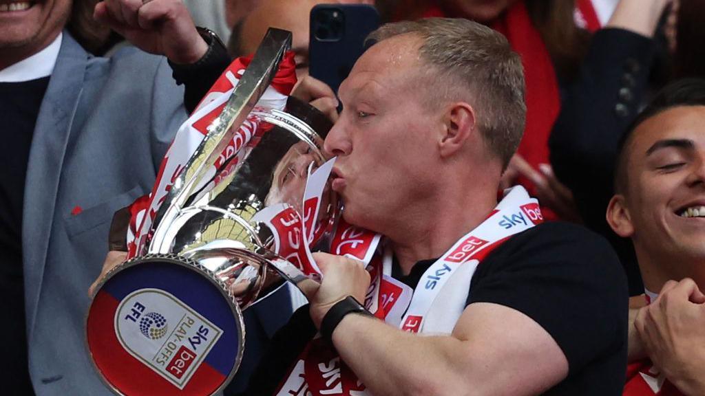 Steve Cooper celebrates as he kisses the Championship Playoff trophy after Nottingham Forest's victory at the end of the English Championship play-off final football match between Huddersfield Town and Nottingham Forest at Wembley Stadium in London, on May 29, 2022