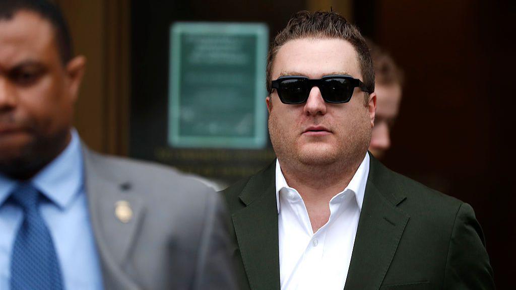 George Kaplan, wearing a white shirt and grey jacket, walks out of court.
