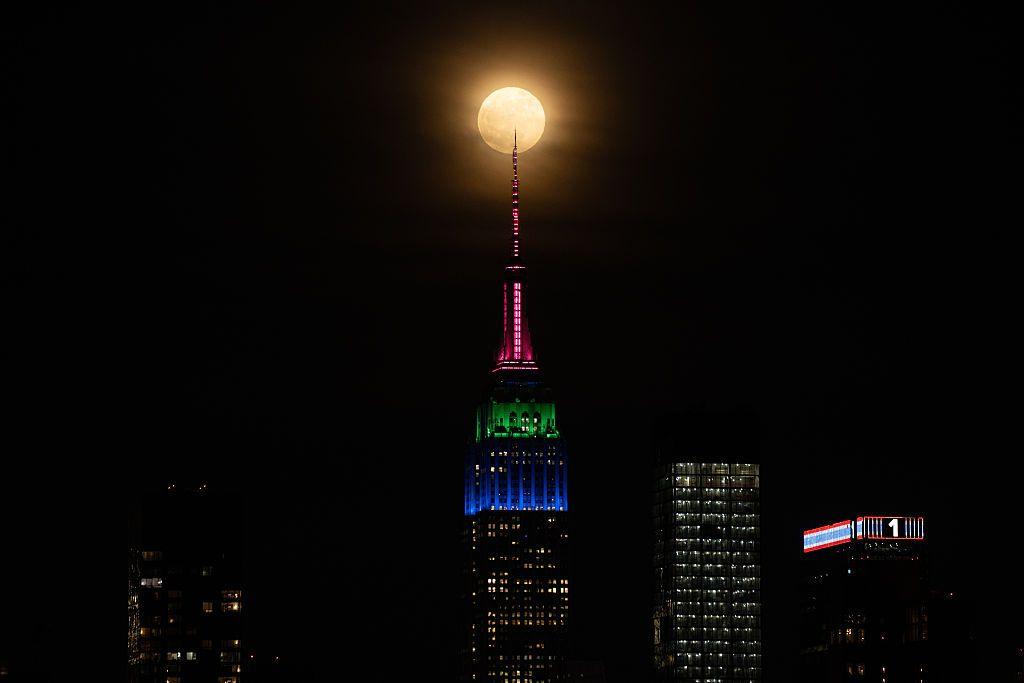 The full Flower Moon rises behind the skyline of midtown Manhattan and the Empire State Building in New York City on May 12, 2025