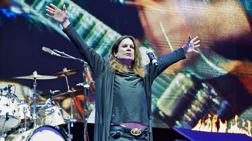 Osbourne saluting the crowd on stage with Black Sabbath