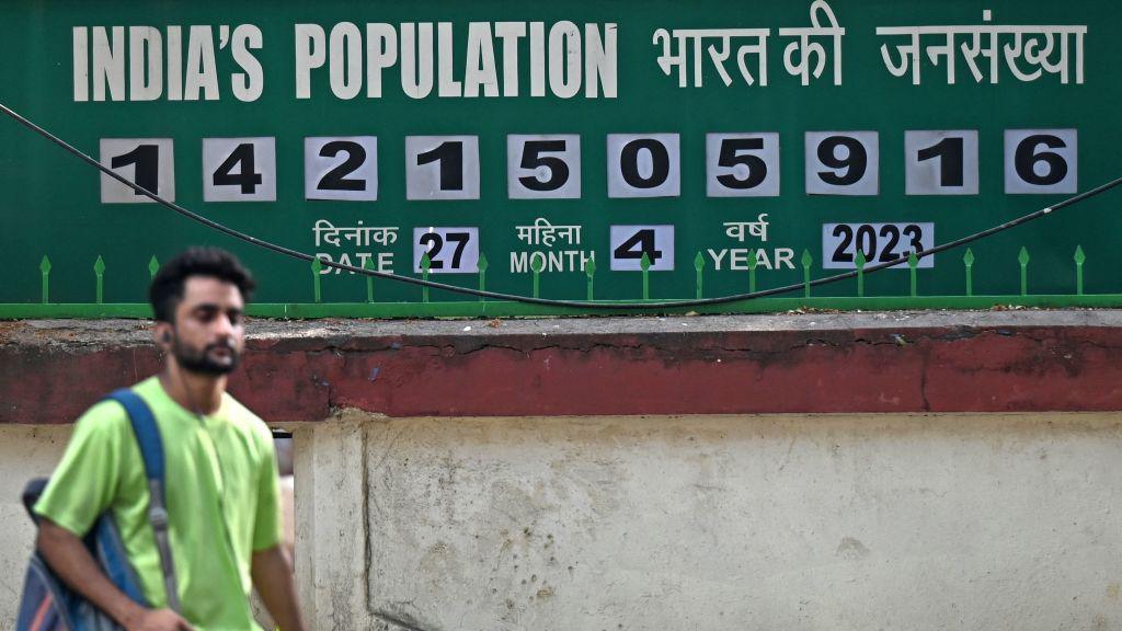 A pedestrian walks past a population clock board displayed outside the International Institute for Population Sciences (IIPS) in Mumbai on April 27, 2023.