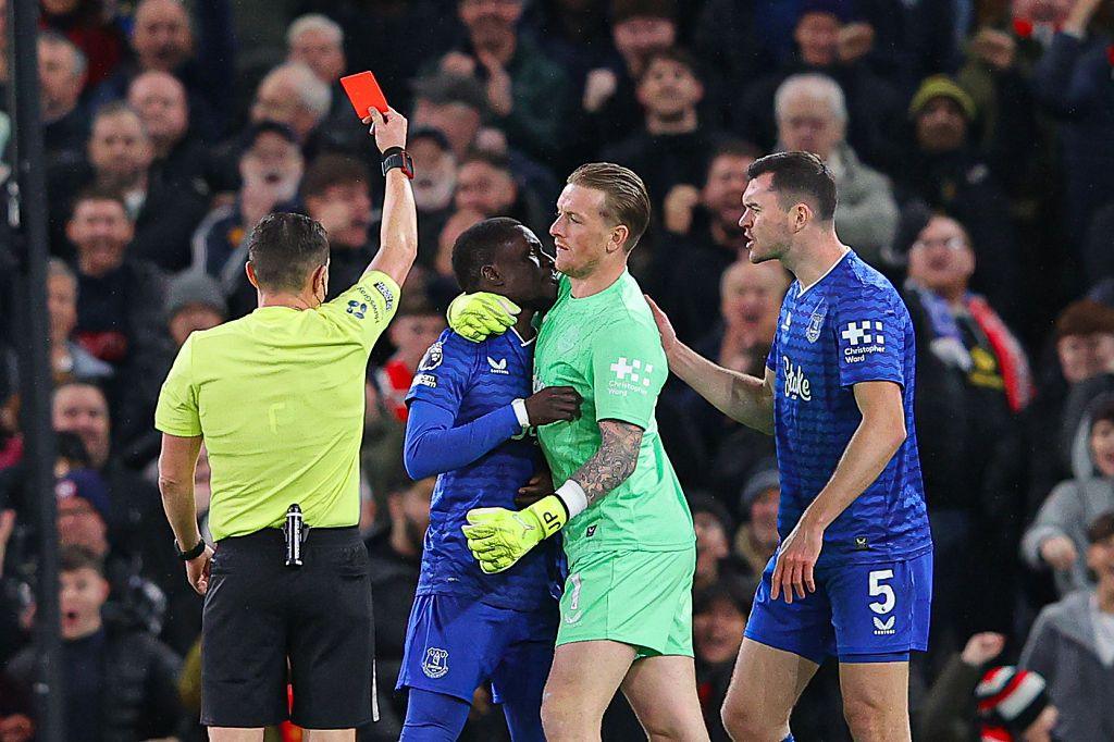 Idrissa Gueye of Everton is held back by Jordan Pickford of Everton as he is shown a red card by referee Tony Harrington for an altercation with teammate Michael Keane.