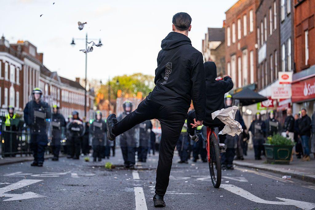 A man stands in the middle of a road in Epsom opposite riot police during a protest.