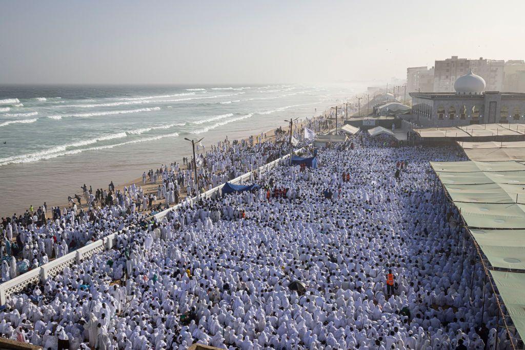 Hundreds of people dressed in white take part in a religious ceremony at a premises on the beachfront.