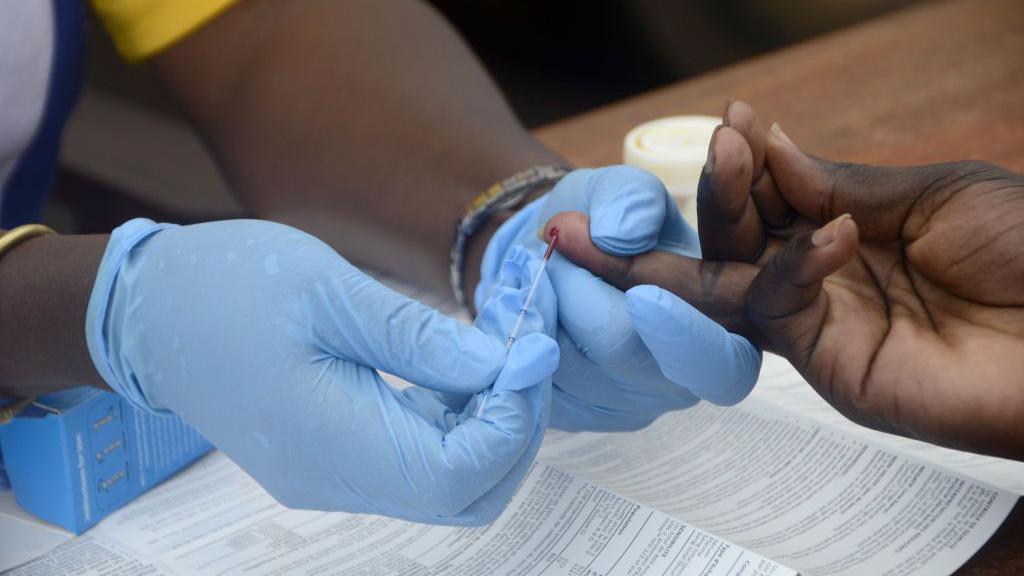 A close-up shot of a health worker's hands taking a blood sample from a participant for Aids testing in Uganda.