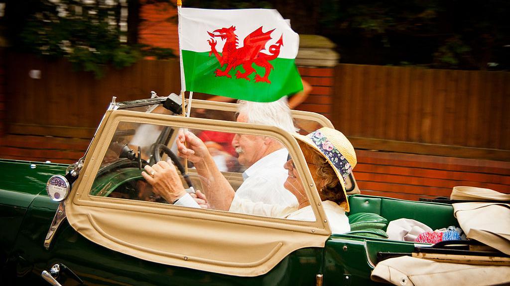 Elderly couple in car flying flag