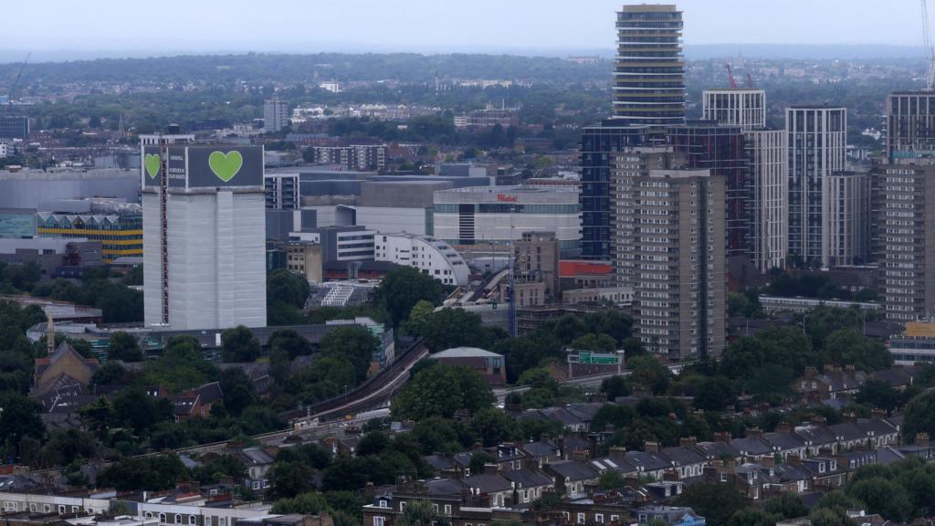 A wide shot showing the covered remains of Grenfell Tower amongst residential housing