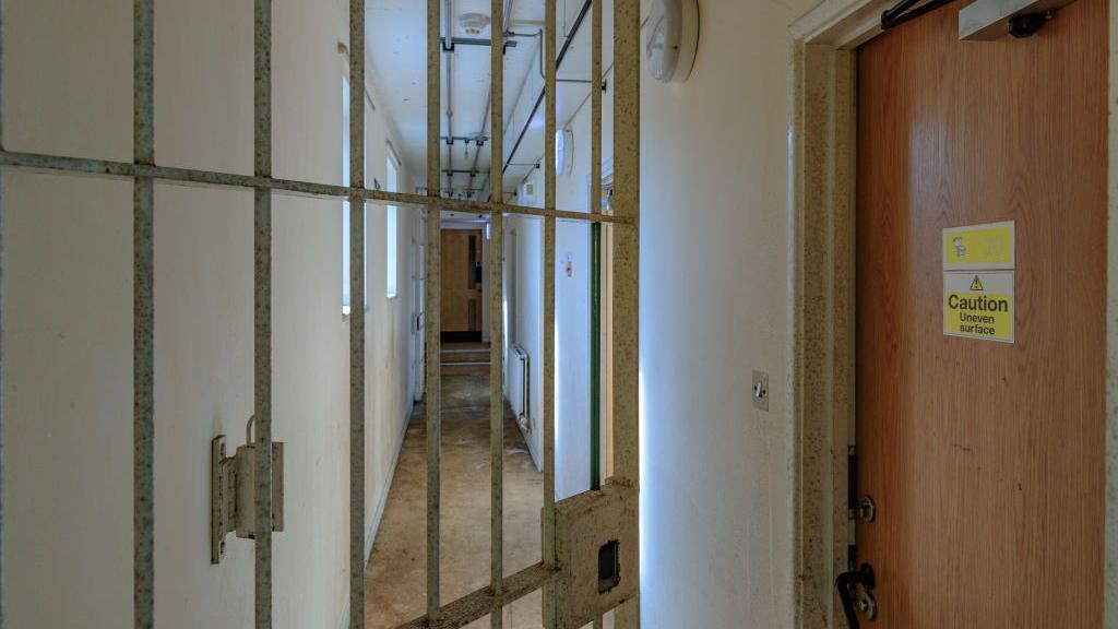 An open gate and a door with "caution: uneven surface" at Campsfield House