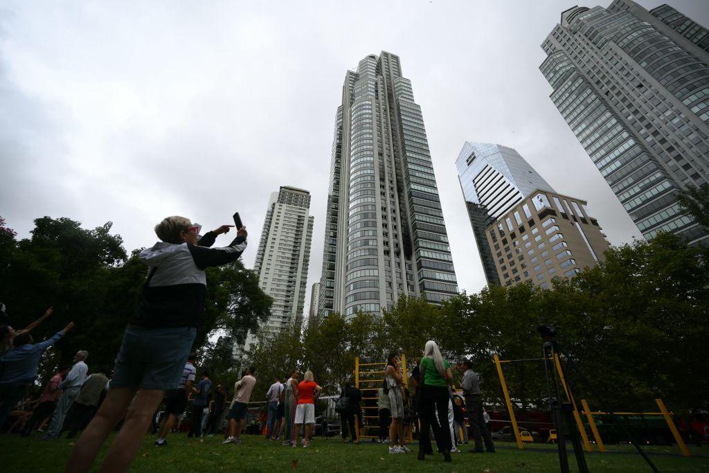 People look at a skyscraper after dozens of people were evacuated from the 50-story apartment building that caught fire at Puerto Madero in Buenos Aires on 11 February 2025