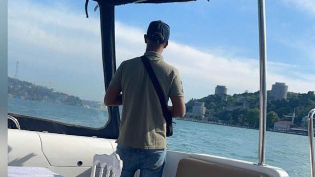 Shazad Miah on a boat. He is facing away from the camera and wearing a sun cap, polo shirt and jeans.