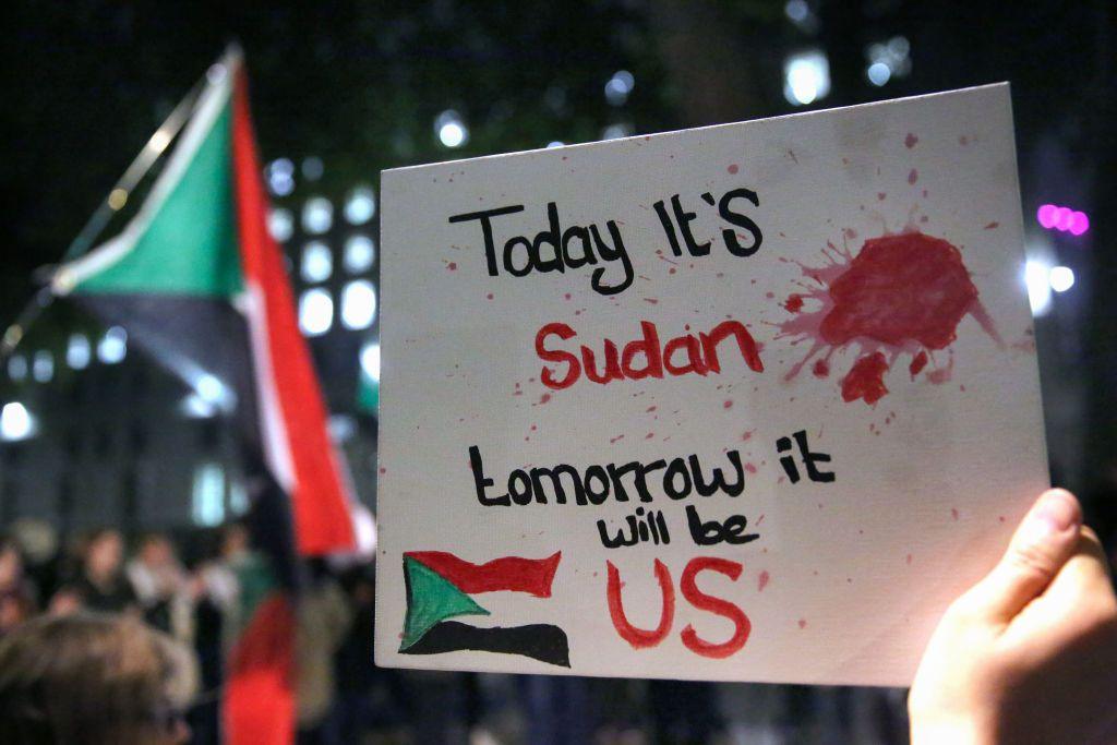 A protester holds a sign that reads 'Today it's Sudan, Tomorrow it will be US' during a demonstration. 