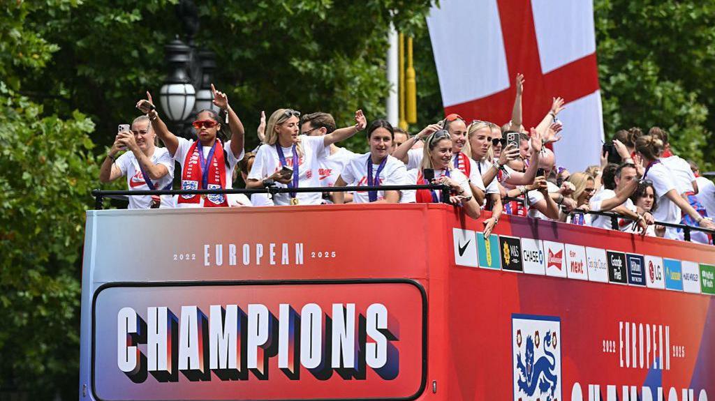 The bus carrying the England women's national football team drives along the Mall during the homecoming victory parade near Buckingham Palace