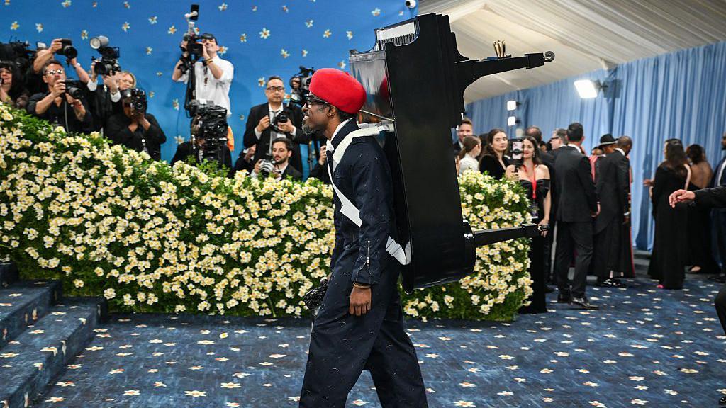 Musician Andre 3000 with a piano strapped to his back for his met gala look