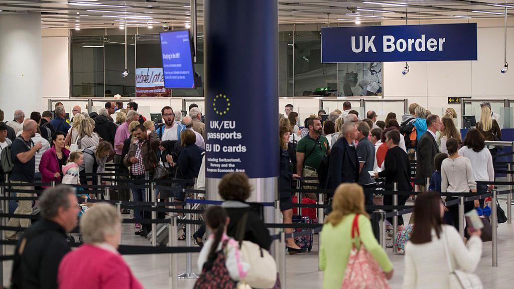 Queue of people waiting to pass UK border checks at an airport in London