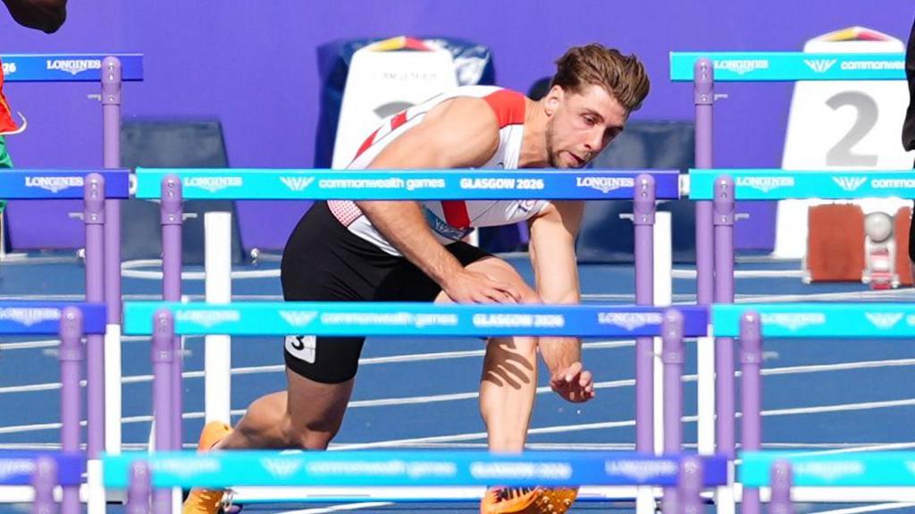 Evan Campbell falls in the 110m hurdles